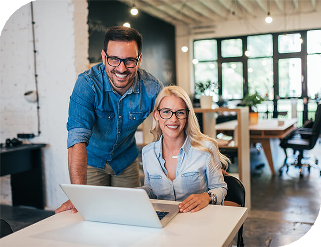 Man and Women smiling at a desk behind a computer.